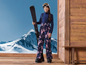 Een meisje met skikleding en een ski houdt een ski vast.