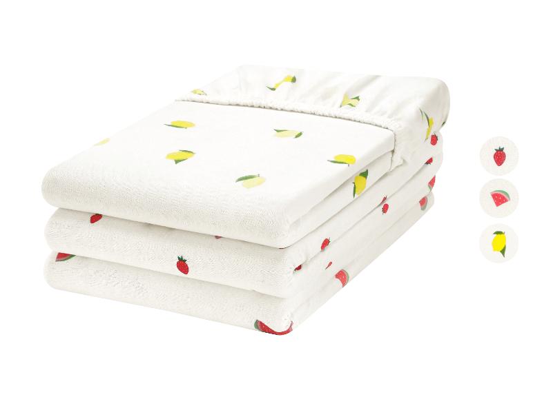Draps-housses blancs pliés avec motifs de citrons, fraises et pastèques.