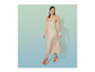 Een vrouw draagt een beige jurk en bruine sandalen met plateauzool.