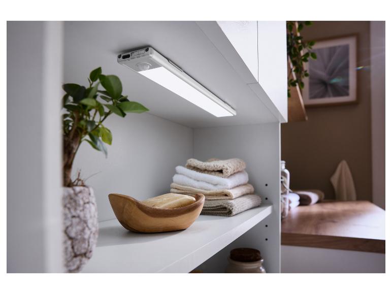 Een LED-kastlamp met bewegingssensor gemonteerd onder een witte kast, met handdoeken en zeep.