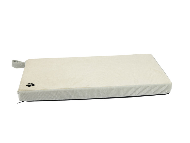 Een beige hondenbed met een zwarte pootprint.