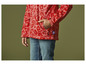 Een kind draagt ​​een rood jack met bloemenprint en blauwe jeans.