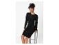 Femme en robe noire scintillante, assise sur un tabouret.