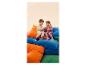 Deux enfants en survêtements et baskets assis sur des coussins colorés.