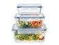 Récipients alimentaires en verre empilés avec couvercles, remplis de salade, concombre et carottes.