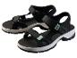 Une paire de sandales de sport noires avec des accents verts sur fond blanc.