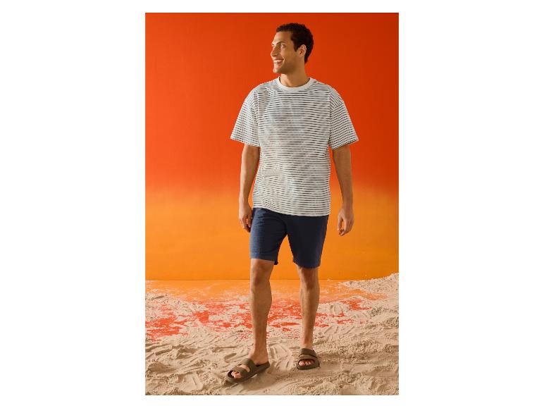 Homme souriant en t-shirt rayé ESMARA MEN et short sur la plage.