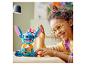 Lachend kind speelt met een LEGO Stitch figuur die een ijsje vasthoudt.