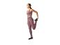 Femme en leggings et brassière de sport violets, s'étirant.