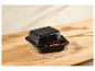 Plat à rôtir noir avec couvercle, contenant des fruits coupés, sur un dessous de plat en paille.