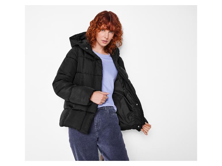 Roodharige vrouw in een zwarte pufferjas en jeans.