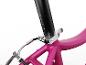 Close-up van een roze fietsframe met een zwarte zadelpen en zilveren klem.