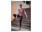 Femme en tenue de sport violette et noire faisant du yoga sur un tapis gris.