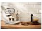Een retro-stijl crèmekleurige espressomachine die koffie zet in twee kleine glazen op een houten aanrecht.