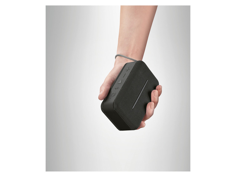Een hand die een zwarte draagbare Bluetooth-luidspreker vasthoudt.