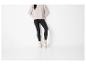 Femme en pull beige, leggings noirs et baskets blanches avec chaussettes à volants