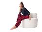 Lachende vrouw in rood geruite pyjama en zwart shirt, zittend op een witte stoel.