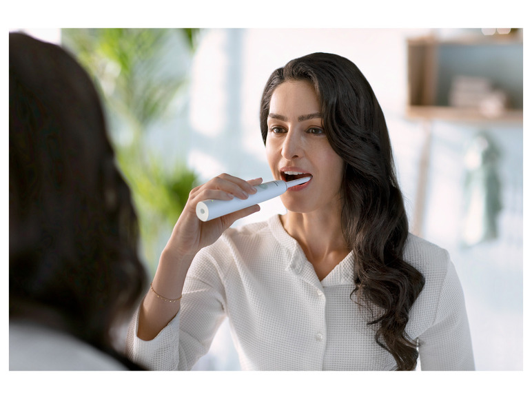 Een vrouw poetst haar tanden met een elektrische tandenborstel van Oral-B.