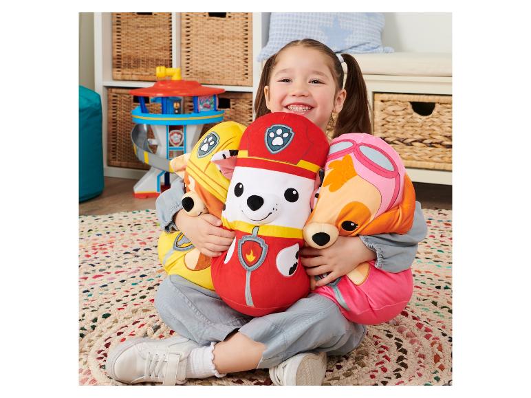 Een meisje met Paw Patrol knuffels, waaronder Chase, Marshall en Skye.