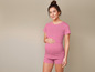 Een zwangere vrouw draagt een roze T-shirt en korte broek.
