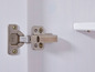 Een Hettich scharnier voor een witte kastdeur.