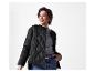 Femme en veste matelassée noire, pull gris et jeans.