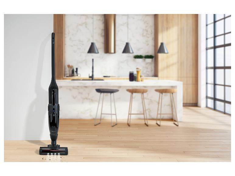 Zwarte draadloze stofzuiger met LED-verlichting op een houten vloer in een moderne keuken