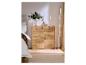 Commode en bois avec tiroirs et portes, décorée d'un vase de fleurs et de bougies, à côté d'un lit.