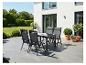 Ensemble de mobilier de jardin: table et quatre chaises sur une terrasse, entouré de verdure.