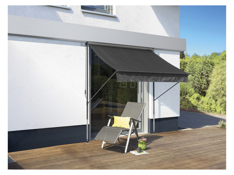 Een zwarte zonwering voor een terras met een ligstoel.