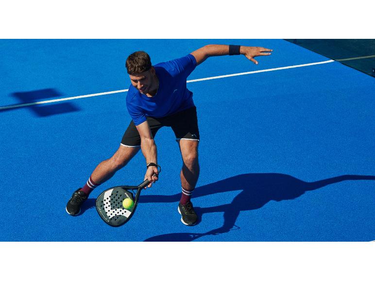 Homme en tenue de sport jouant au padel sur un court bleu.