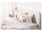 Een bed met roze bloemen beddengoed en kussens.