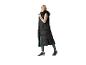 Vrouw in een lange zwarte gewatteerde bodywarmer met capuchon, beige blouse en bedrukte legging.