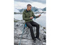 Homme en sweat-shirt vert et pantalon noir, regardant des bâtons de randonnée dans les montagnes.