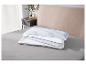 Taies d'oreiller et protège-matelas empilés sur un lit.
