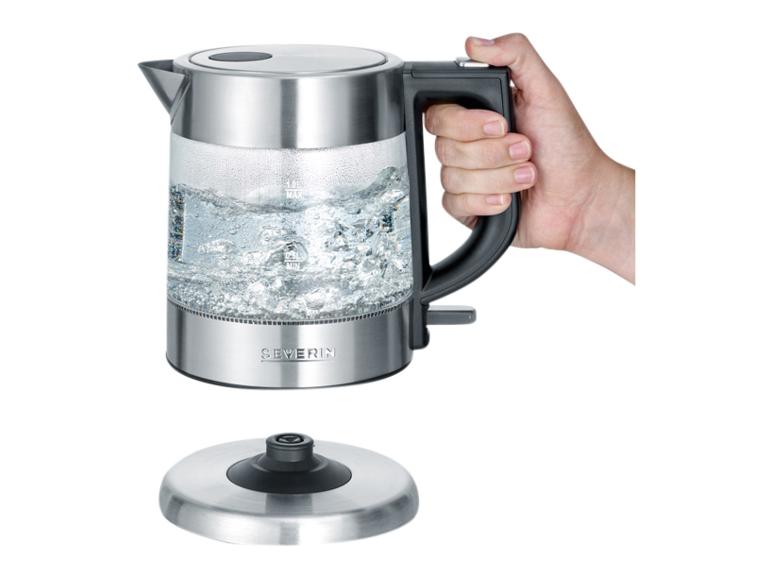 Bouilloire électrique en verre Severin avec de l'eau bouillante, tenue par une main, à côté de la base.