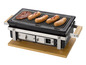 Een zwarte grill met vier worstjes en een stuk vlees erop.