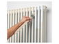 Een hand die een radiator met een verfkwast van Parsijoe schildert.