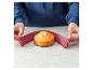 Een ronde cake op een glazen plaat, met twee roze flexibele taartvormen.