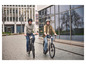 Twee mensen rijden op elektrische fietsen in de stad.