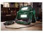 Projecteur de travail PARKSIDE chargeant un smartphone sur une table en bois.