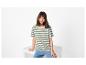 Femme en t-shirt rayé et jean assise sur un cube blanc.