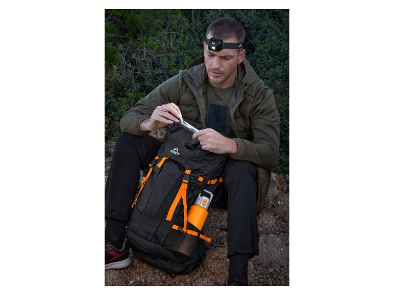 Man met hoofdlamp en Crivit rugzak, haalt een multitool tevoorschijn.