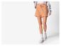 Femme portant un short de sport orange clair et des baskets blanches.
