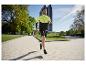 Homme courant dans un parc, portant une veste de course bicolore et un short noir.