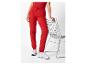Femme en jogging rouge et baskets blanches, appuyée sur une chaise.