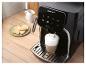 Machine à café noire avec verre de latte et biscuits sur une table en bois.