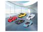Vijf speelgoed Lamborghini auto's in diverse kleuren op een showroomvloer met uitzicht op de oceaan.