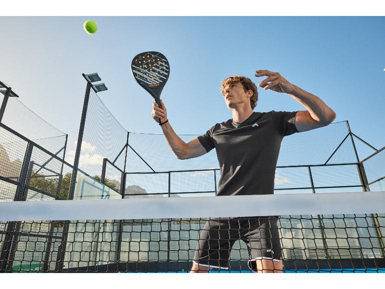 Man speelt padel, houdt een padelracket vast, met een tennisbal in de lucht.