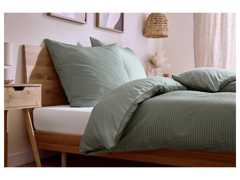 Slaapkamer met bed, saliegroen wafelgeweven beddengoed en bijpassende kussens.